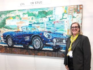 Automotive artist Lyn Hiner smiling beside her hand-painted blue Ferrari 250 GT SWB California Spyder artwork at the RetroAuto Pavilion, Pebble Beach Concours d'Elegance 2026